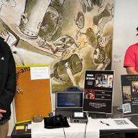 Two event attendees standing next to book and posing for photo